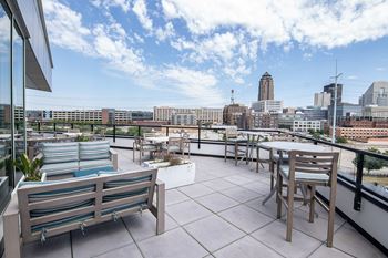 A rooftop patio with a table and chairs overlooking a city skyline.at Linc, Des Moines, IA 50309  